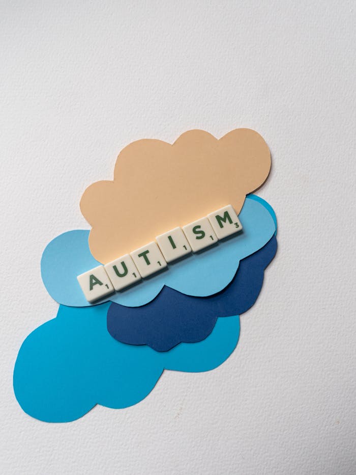 Creative representation of autism awareness using Scrabble tiles and paper clouds on a white background.